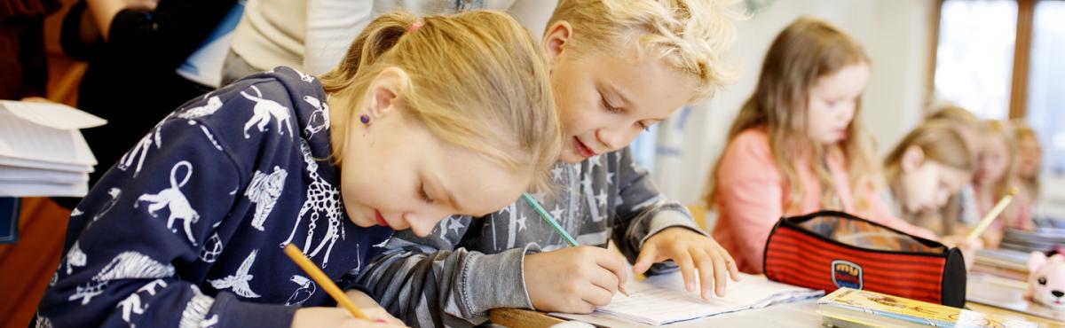 Kakkosluokkalaiset tyttö ja poika tekevät keskittyneinä tehtäviä luokkahuoneessa. 
