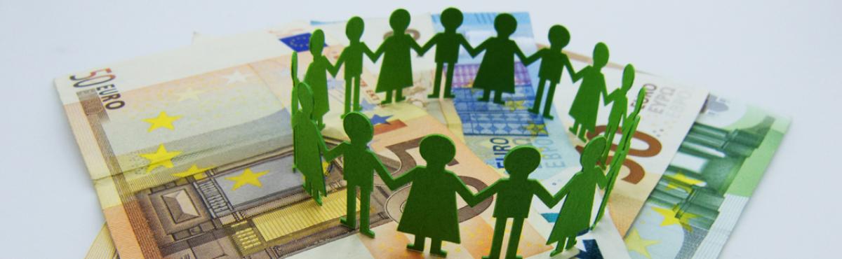 Vihreitä paperista leikattuja ihmishahmoja setelipinon päällä. 