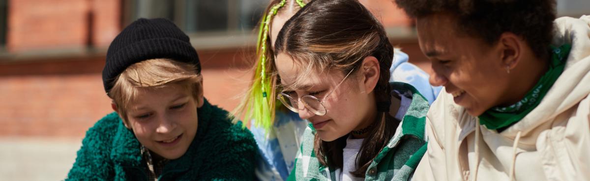 Kolme teiniä istuu ulkona.